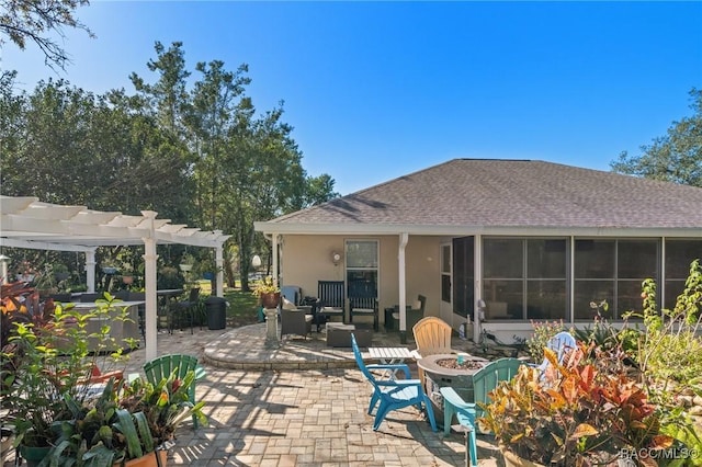 rear view of house featuring a sunroom, a pergola, a patio, and an outdoor fire pit