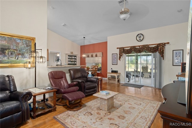 living room with ceiling fan with notable chandelier, light hardwood / wood-style flooring, vaulted ceiling, and sink