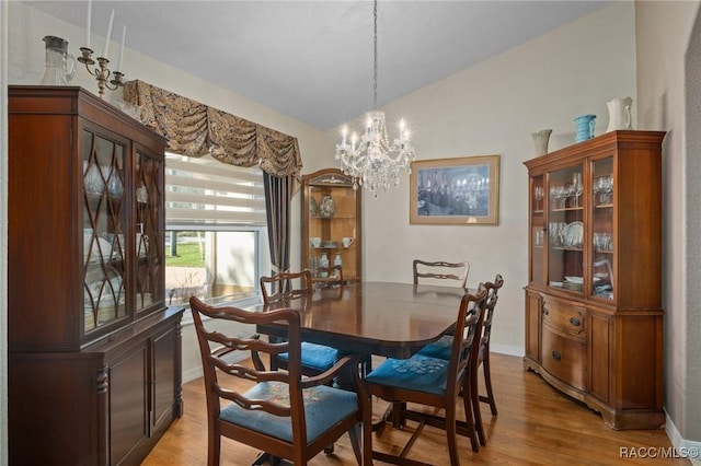 dining room featuring a chandelier, light hardwood / wood-style floors, and vaulted ceiling