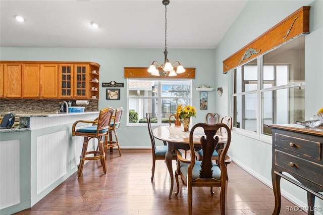 dining area with dark wood-type flooring, sink, and a notable chandelier