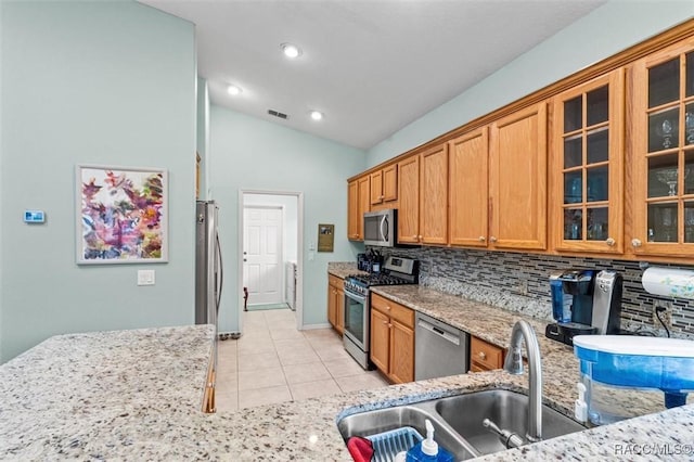 kitchen featuring sink, light stone counters, light tile patterned floors, appliances with stainless steel finishes, and decorative backsplash