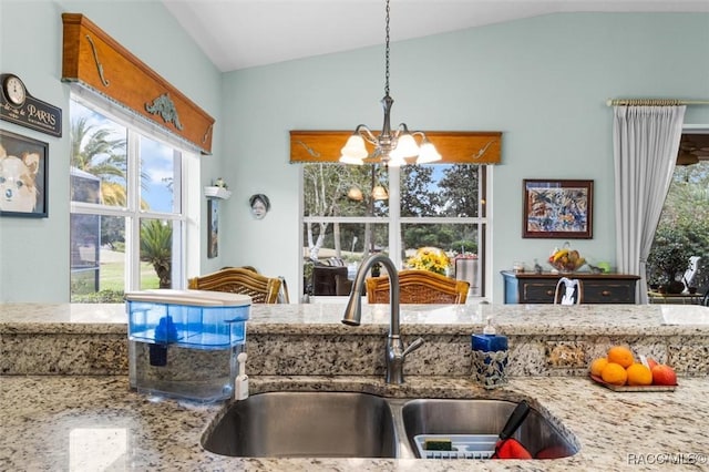 kitchen with decorative light fixtures, lofted ceiling, sink, a chandelier, and light stone counters