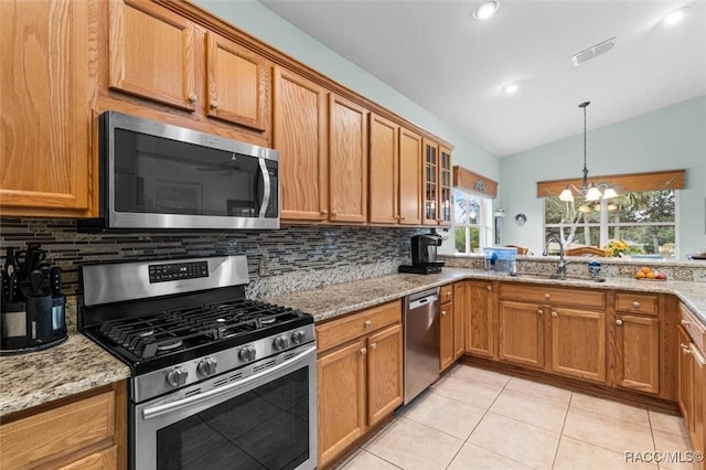 kitchen featuring light stone counters, vaulted ceiling, stainless steel appliances, and tasteful backsplash