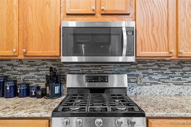 kitchen with stainless steel appliances, backsplash, and light stone counters