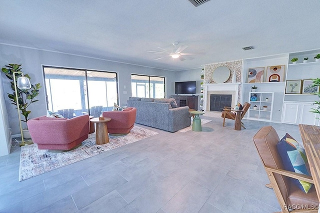 living room featuring built in features, a large fireplace, and ceiling fan