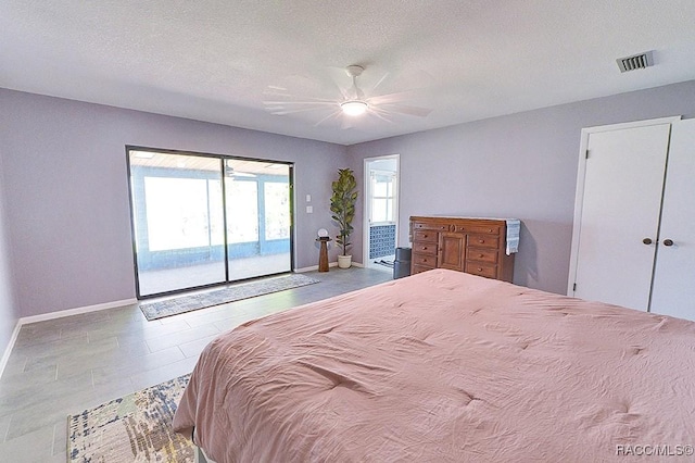 bedroom featuring ceiling fan, access to exterior, and a textured ceiling