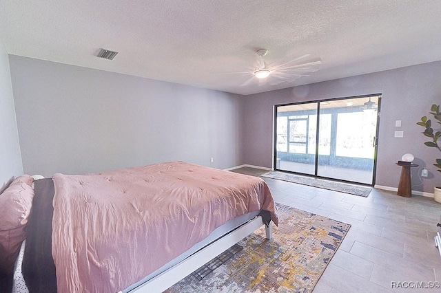 bedroom with ceiling fan, access to outside, and a textured ceiling