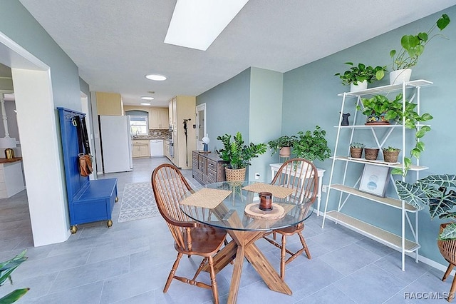 dining room with light tile patterned floors and a skylight