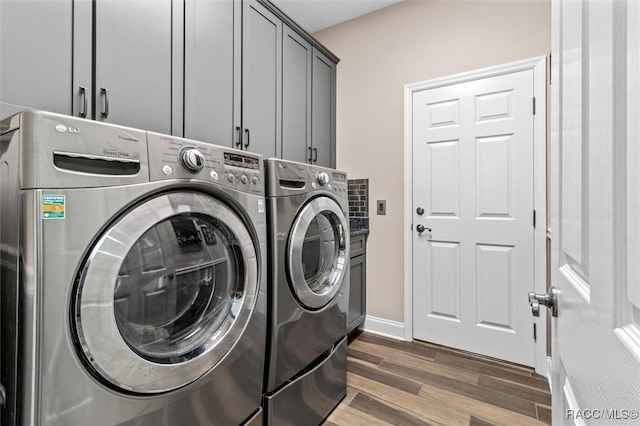 laundry area with washer and dryer, cabinets, and dark wood-type flooring