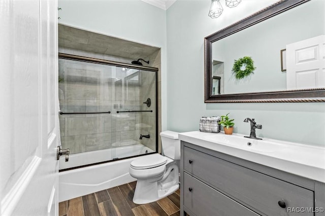 full bathroom with hardwood / wood-style floors, vanity, toilet, and shower / bath combination with glass door