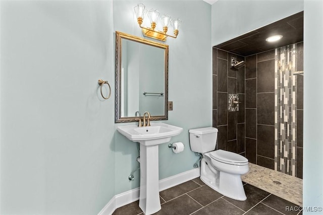 bathroom with tile patterned flooring, a tile shower, toilet, and sink