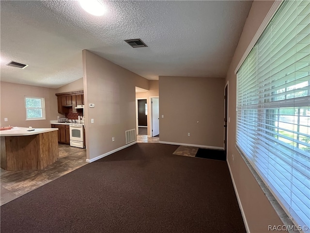 unfurnished living room with dark carpet, a textured ceiling, and vaulted ceiling