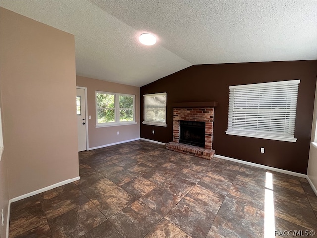 unfurnished living room with a textured ceiling, a fireplace, and lofted ceiling