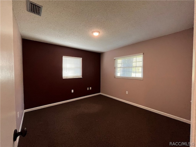 carpeted empty room featuring a textured ceiling