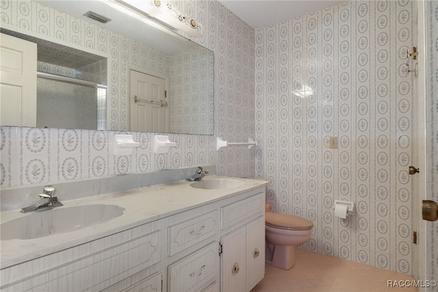 bathroom featuring tile patterned floors, vanity, a shower with shower door, and toilet