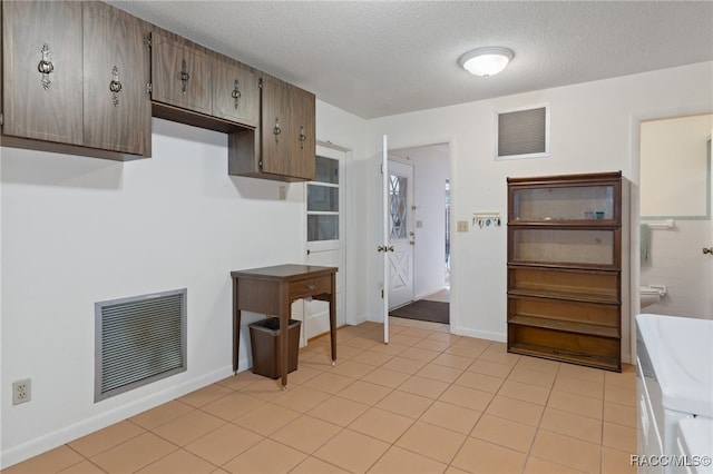 kitchen featuring light tile patterned flooring, dark brown cabinetry, and a textured ceiling