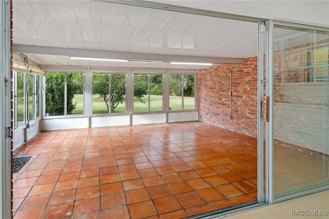 unfurnished sunroom featuring beam ceiling