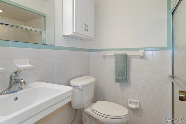 bathroom with toilet, sink, and tile walls