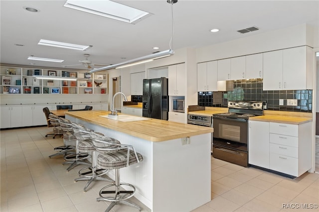 kitchen featuring black refrigerator, sink, white cabinetry, and range with electric cooktop