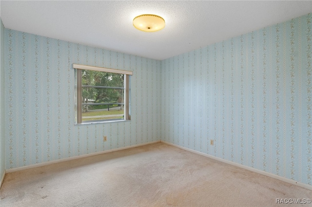 carpeted empty room featuring a textured ceiling