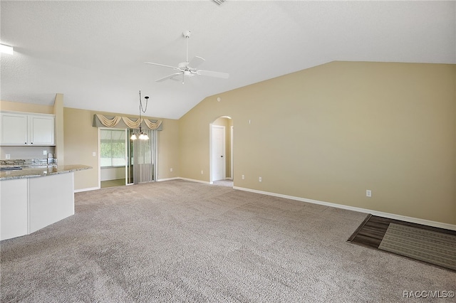 unfurnished living room with ceiling fan with notable chandelier, light colored carpet, and lofted ceiling