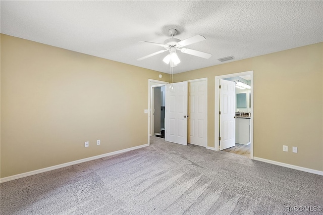 unfurnished bedroom with a textured ceiling, light colored carpet, and ceiling fan