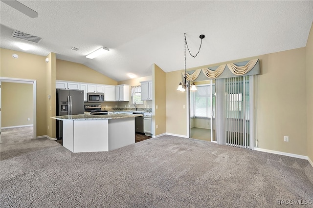 kitchen featuring white cabinets, a kitchen island, lofted ceiling, and appliances with stainless steel finishes