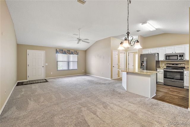 kitchen with decorative light fixtures, a center island, stainless steel appliances, and white cabinetry