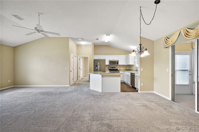 kitchen with pendant lighting, sink, vaulted ceiling, white cabinetry, and stainless steel appliances