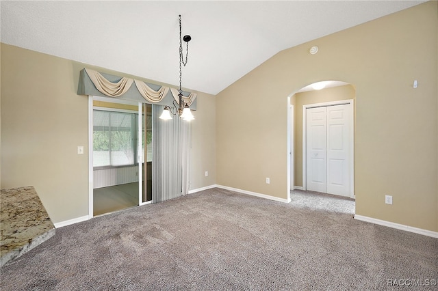 spare room featuring carpet flooring, a chandelier, and vaulted ceiling