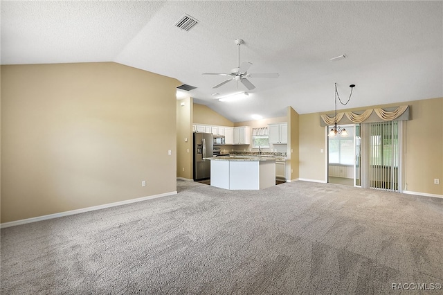 unfurnished living room featuring a textured ceiling, ceiling fan with notable chandelier, light colored carpet, sink, and lofted ceiling