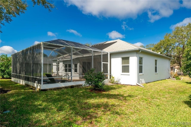 back of house featuring a lawn, a lanai, and stucco siding