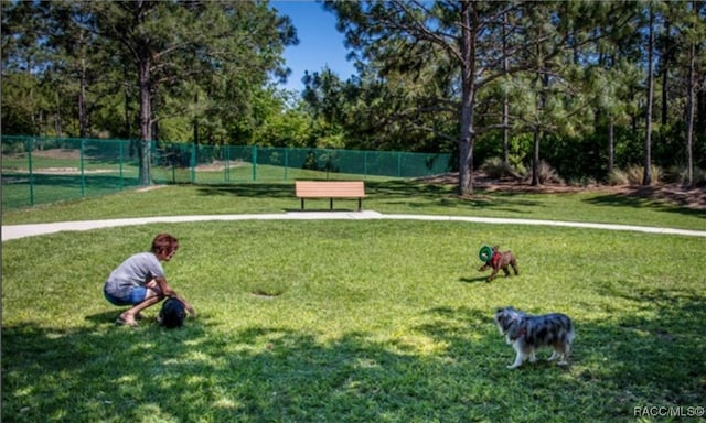 view of home's community with a yard and fence