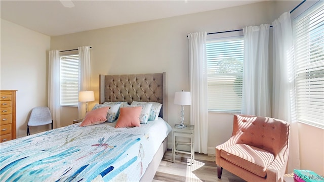 bedroom featuring multiple windows, baseboards, and wood finished floors