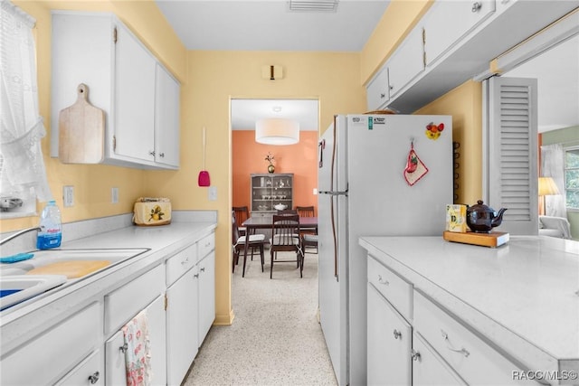 kitchen featuring white cabinetry, sink, and white fridge