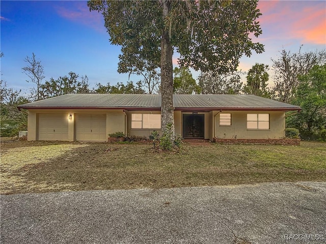 ranch-style house featuring a lawn and a garage