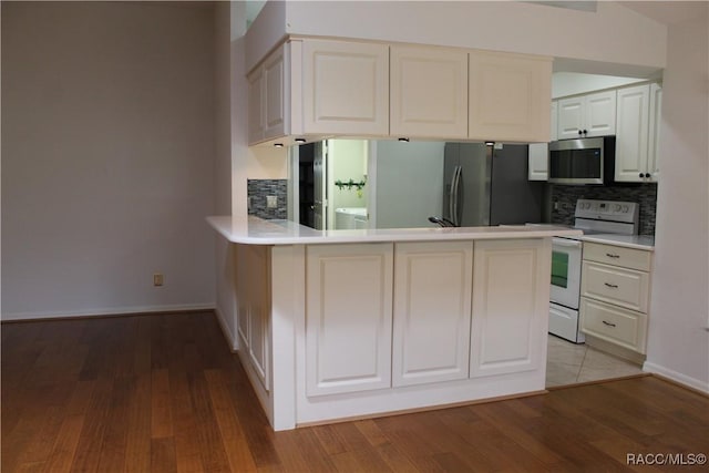 4614 N Webster Island Ter, Hernando, FL 34442 - kitchen with white range with electric stovetop, stainless steel microwave, freestanding refrigerator, decorative backsplash, and a peninsula