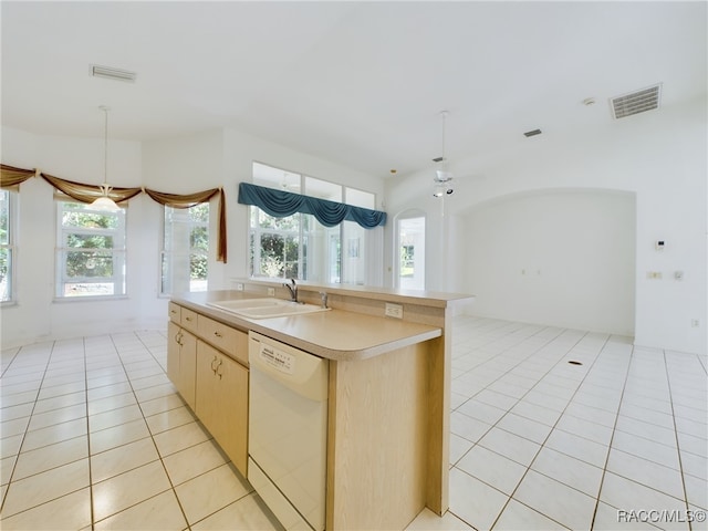 kitchen with white dishwasher, sink, light brown cabinets, light tile patterned floors, and an island with sink