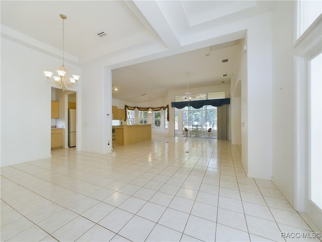 tiled spare room with ceiling fan with notable chandelier