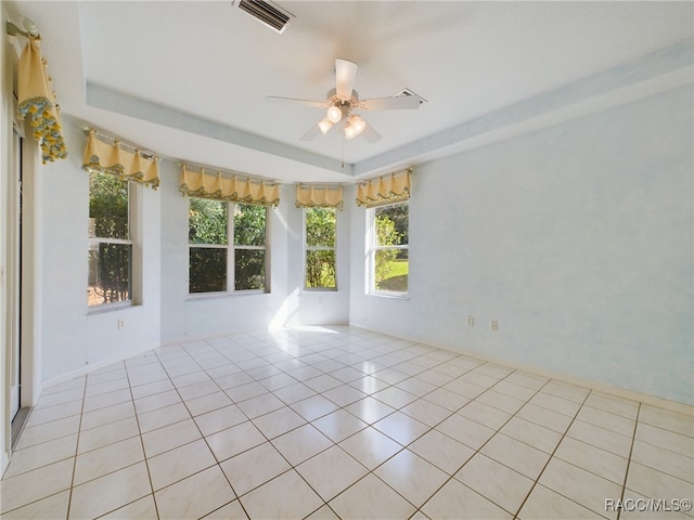 unfurnished room with ceiling fan, a raised ceiling, and light tile patterned floors