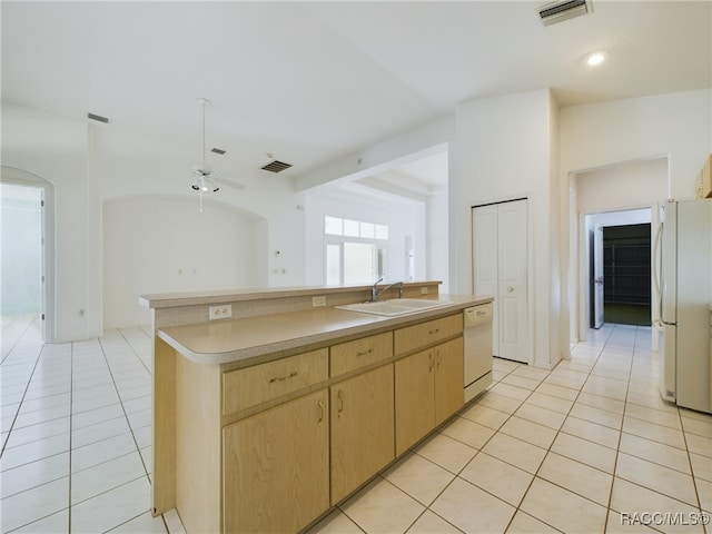 kitchen featuring white appliances, sink, light tile patterned floors, an island with sink, and light brown cabinetry