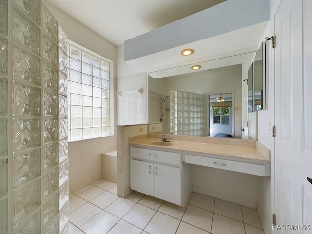 bathroom with tile patterned flooring, vanity, a healthy amount of sunlight, and tiled shower