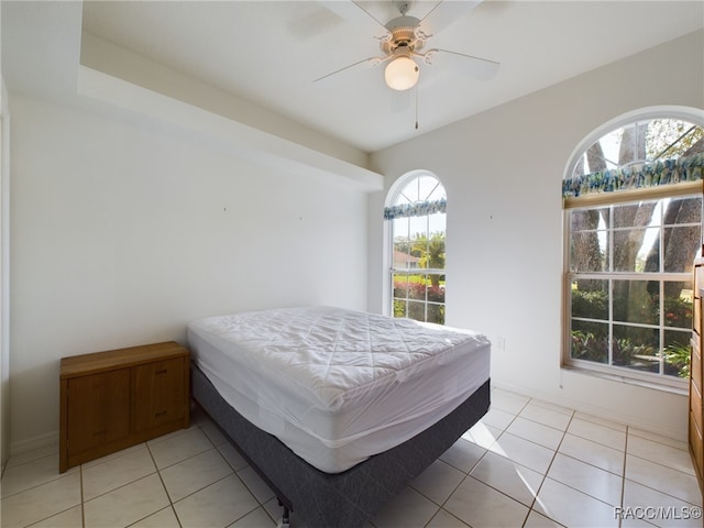 bedroom featuring ceiling fan, light tile patterned floors, and multiple windows