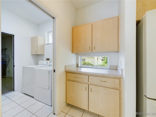 washroom with washing machine and clothes dryer, light tile patterned floors, and cabinets