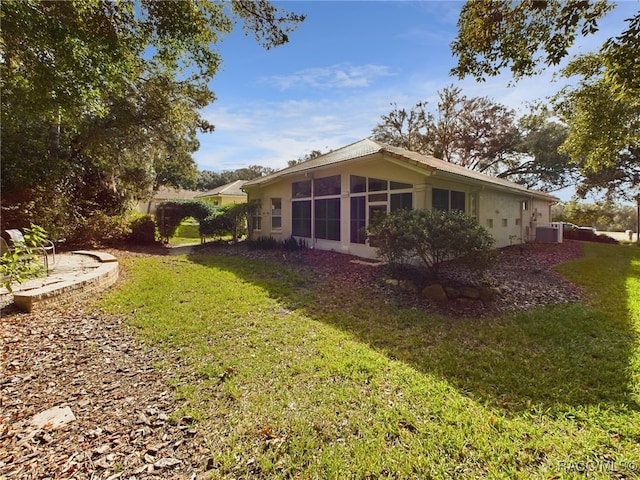 view of yard featuring a sunroom and central AC