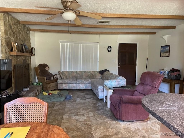 living room with a textured ceiling, a fireplace, visible vents, and beamed ceiling