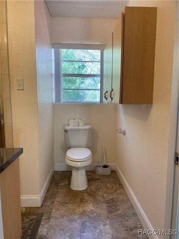 bathroom with baseboards and toilet