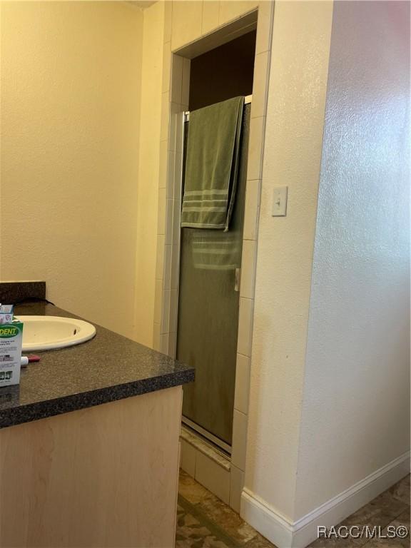 bathroom featuring a shower stall, vanity, and baseboards