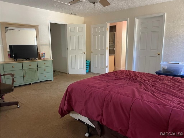 bedroom featuring a ceiling fan, visible vents, a textured ceiling, and light colored carpet