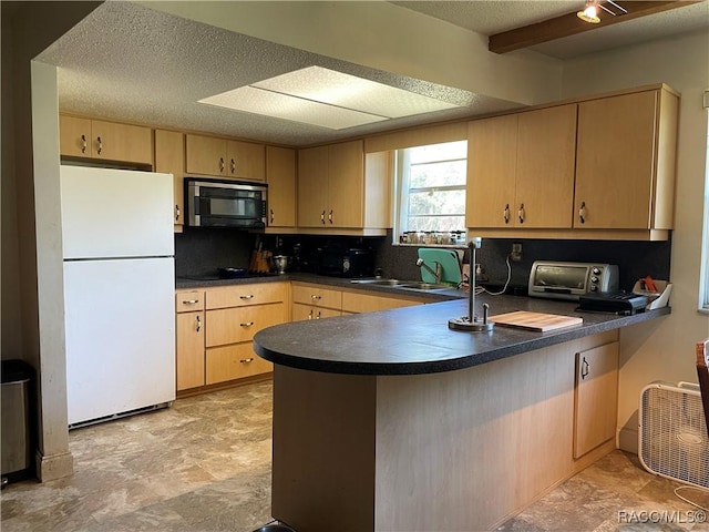 kitchen with dark countertops, black appliances, light brown cabinetry, and a peninsula